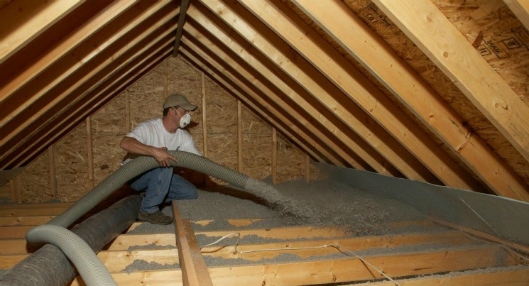 Man blowing insulation into an attic space
